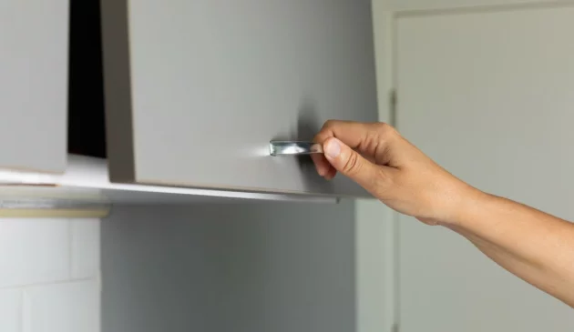 A woman's hand opens a cupboard