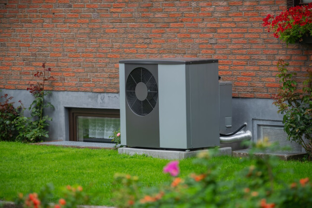 A grey heat pump sits in a UK home's garden