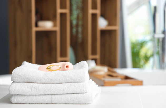A picture of a vibrator laid upon towels in a bathroom