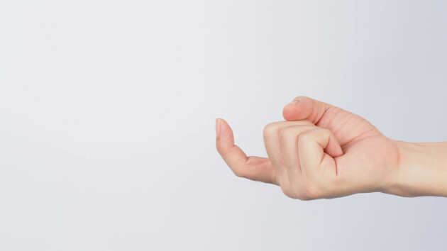 A hand making the come hither position against a grey background