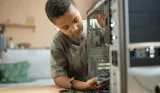 A boy is looking inside a PC he is building at home