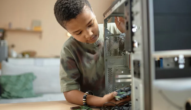 A boy is looking inside a PC he is building at home