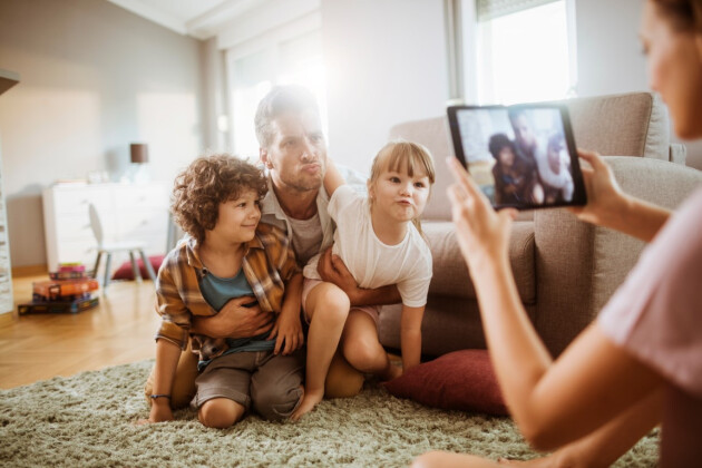A mother takes a picture of her husband and kids pulling funny faces