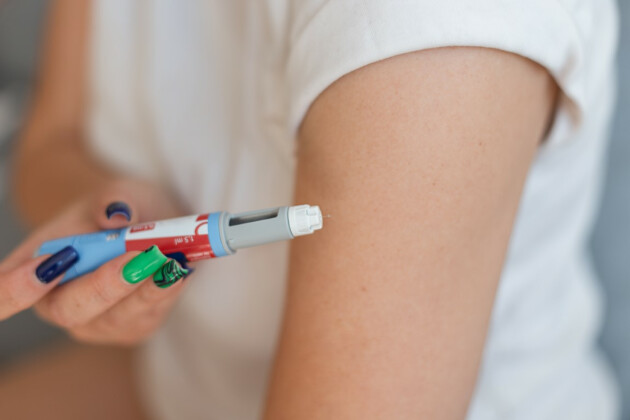 A woman holds an ozempic needle against her arm