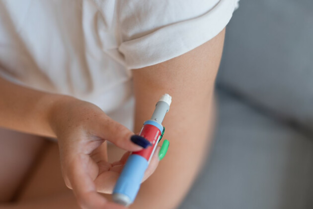 A woman injects her arm with a weight loss pen