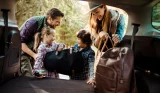 A family loading bags into the boot of their car
