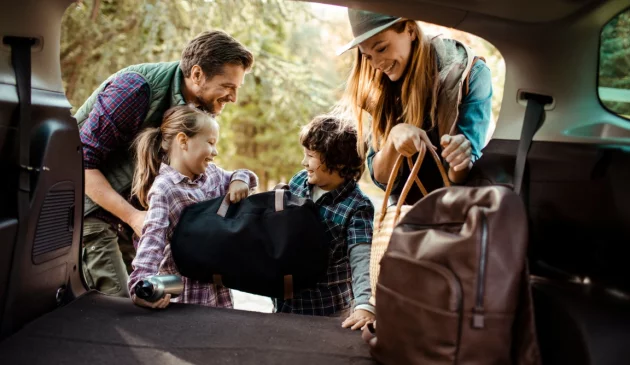 A family loading bags into the boot of their car