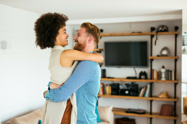 A happy couple embrace in their living room
