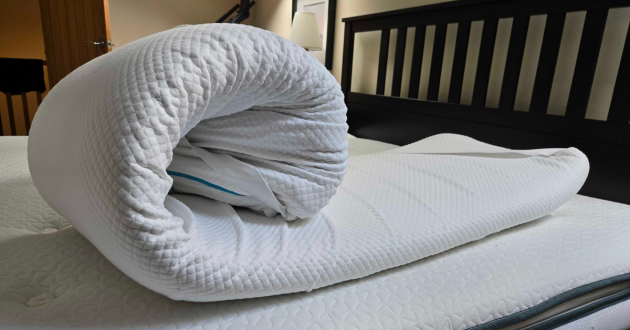 The Simba Cool Foam Mattress Topper curled up on a mattress