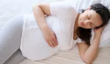 Pregnant woman sleeping in bed on left side