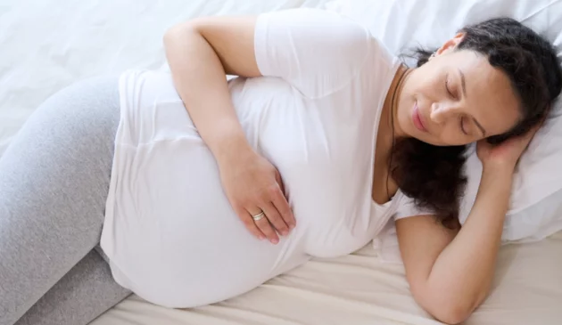 Pregnant woman sleeping in bed on left side