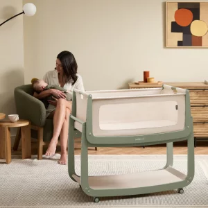 SnuzPod5 crib in green in foreground with mother and baby in background