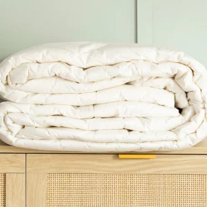 A product image of the Soak & Sleep All Seasons New Zealand Wool Duvet atop a cabinet