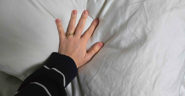 A hand shows how plush the Soak & Sleep Soft as Down pillow really is