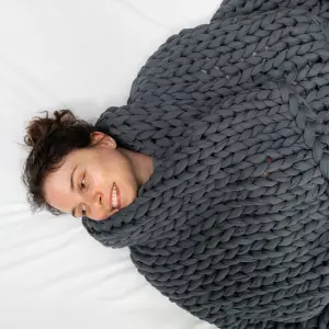 A woman lies underneath a grey Sommio Knitted Weighted Blanket