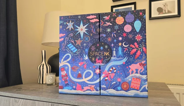 Closed Space NK 2026 Beauty Advent Calendar on a cupboard, with a navy cover decorated in colourful festive illustrations