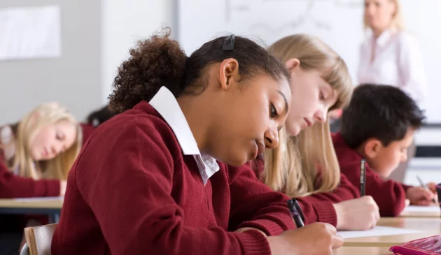 Student writing at her desk at school