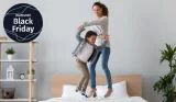 A mother and son bounce on a bed together