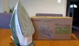 A white and green Tefal Easygliss ECO iron, standing upright on a wooden table next to the recycled cardboard box the product arrived in