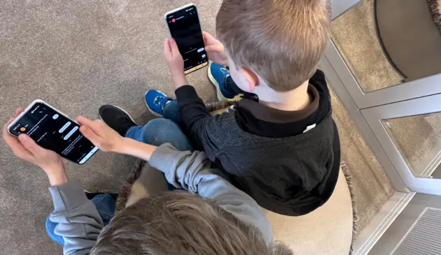 Two children using the Other Phone side by side at home, showing what the child-friendly smartphone looks like in real family use with SafetyMode parental controls