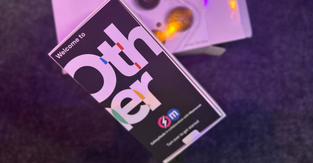 Welcome booklet for the Other Phone, shown on a table during setup, highlighting the onboarding for parents using SafetyMode and child-safe settings