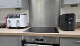 Tower AirX AI 5L air fryer next to a Ninja dual air fryer on a kitchen worktop, showing the size difference.