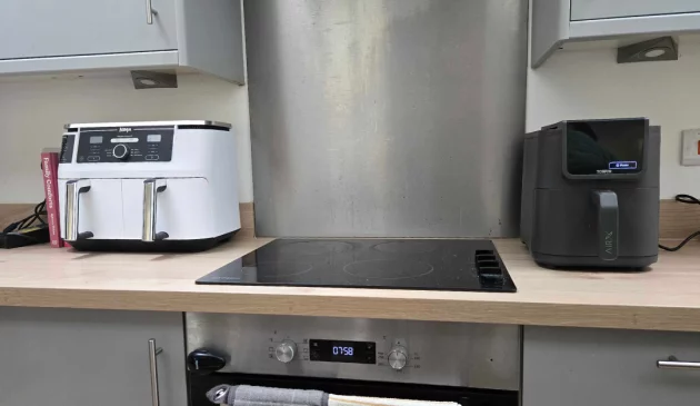 Tower AirX AI 5L air fryer next to a Ninja dual air fryer on a kitchen worktop, showing the size difference.