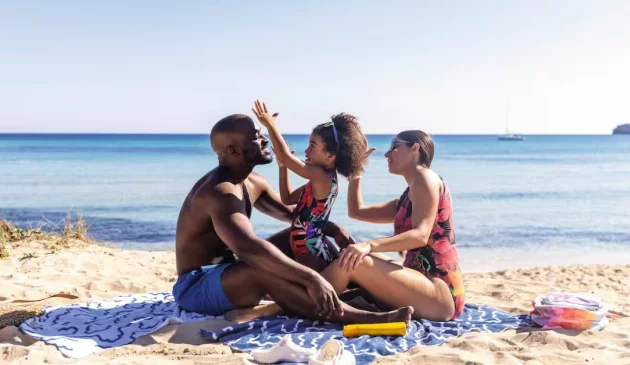 A family sitting on the beach next to the sea