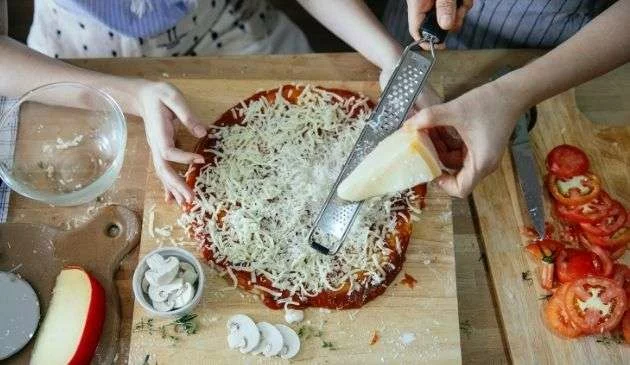 Grating cheese over a pizza