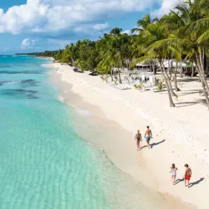 Family walking along a white sandy beach in Dominican Republic