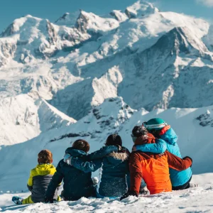Flaine, France - shot of family sitting in the snowing facing a mountain landscape, Mathis Decroux