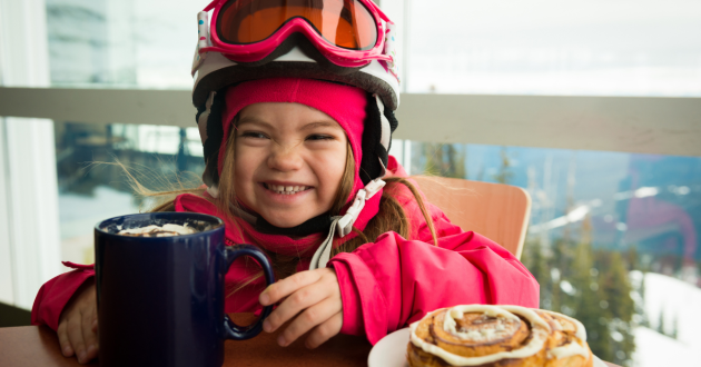 Heidi ski article image: child in ski gear with hot chocolate and pastry