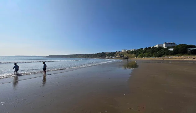 A view of two children playing on Scarborough's south beach with the Esplanade Hotel on the cliff behind