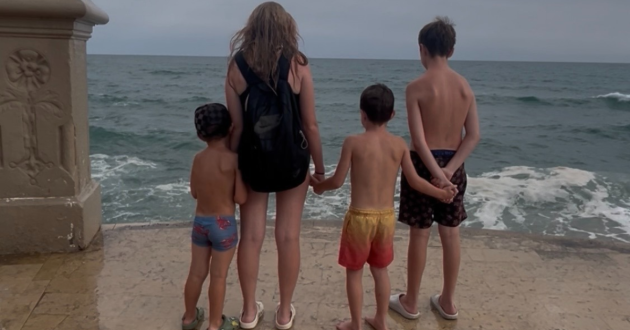 Four children standing on the shoreline at Sitges, waiting for the waves