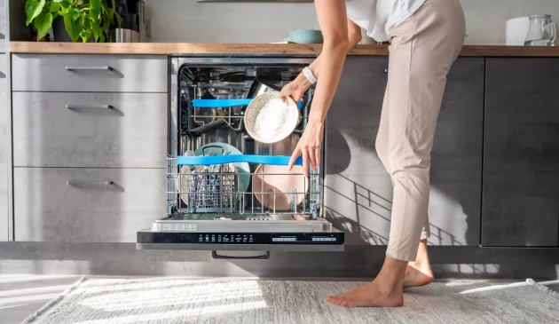Woman loading an integrated dishwasher with pots