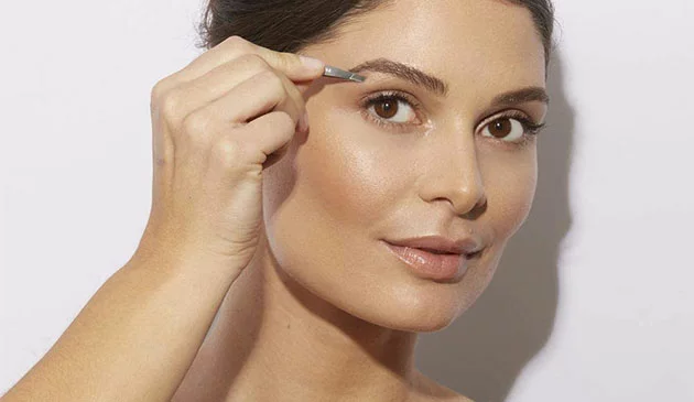 Woman plucking eyebrows
