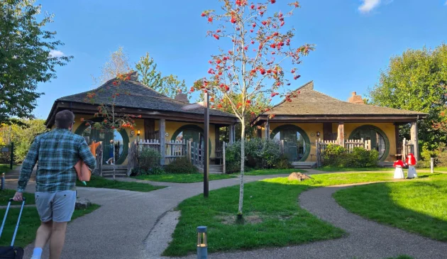 A man walks towards a Woodland Lodge at Alton Towers resort while pulling a suitcase
