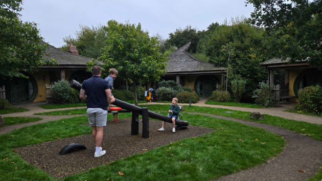 A father plays with his children on seesaw at Alton Towers Woodland Lodges