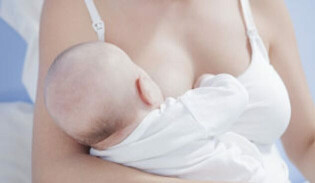 Woman's torso breastfeeding a baby in a nursing top