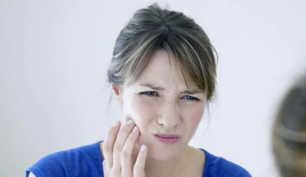Woman with sore tooth holding jaw