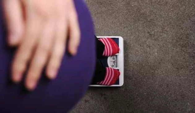 pregnant woman standing on scales