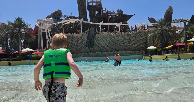 A view from behind a child walking into the wave pool at Yas Waterworld in Abu Dhabi