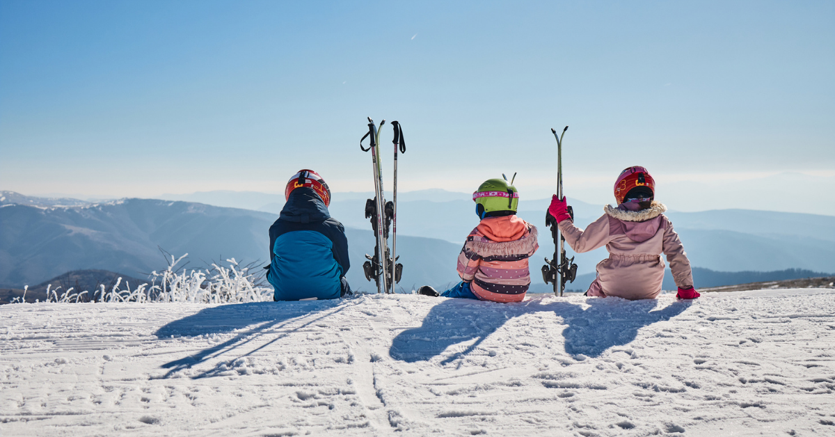 Heidi ski article main image showing three children in ski gear sitting on top of a mountain